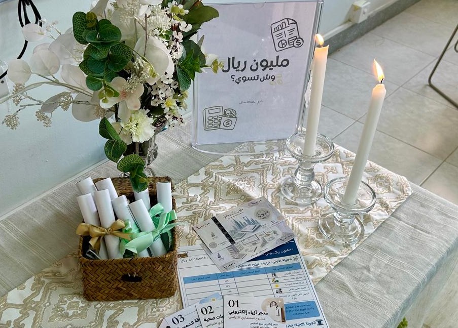 ركن تعريفي بمبادرة "مليون ريال وش تسوي؟" يضم لوحة ومطويات وأفكارًا استثمارية في كلية إدارة الأعمال